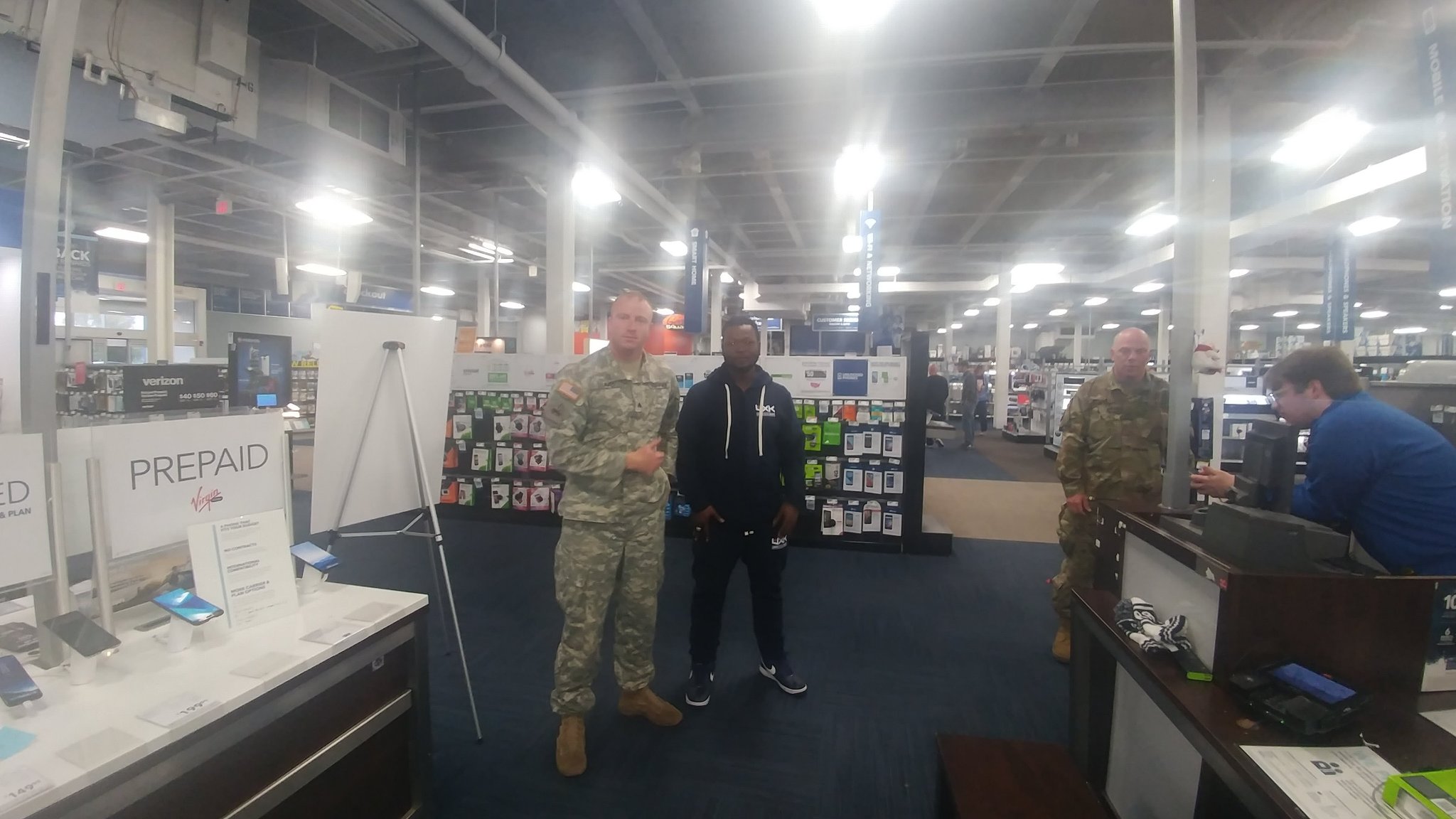 Trav in a UXK hoodie with two US Army soldiers in a store